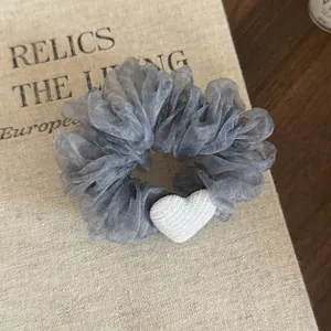 Close-up detail of gray ruffled organza scrunchie featuring a soft white heart accent