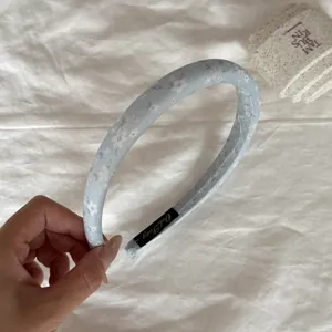 Detailed view of a light blue fabric headband featuring a delicate white floral pattern