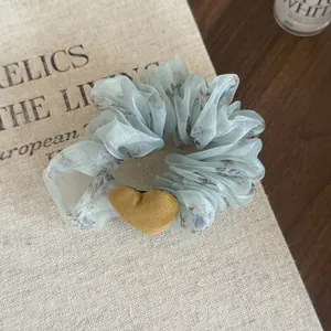 Detailed view of floral organza scrunchie featuring a yellow corduroy heart charm