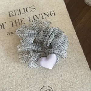 Close-up detail of polka dot mesh scrunchie with a small lavender heart decoration.