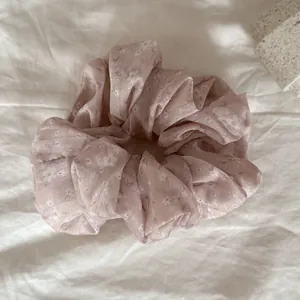 Elegant pink floral scrunchie hair tie with delicate white flower pattern detail