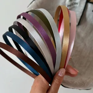 Vista detallada de varias diademas finas de satén de colores de alta calidad sostenidas en la mano