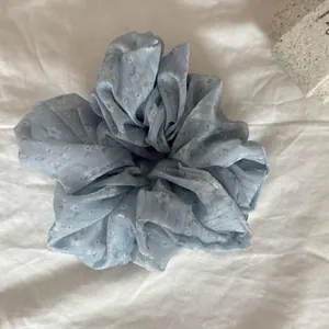 Close-up detail of a light blue floral print scrunchie resting on white fabric