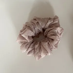 Close-up detail of a pink floral scrunchie hair tie with delicate white flower pattern