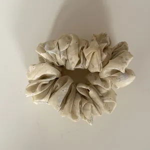 Detail view of a yellow floral scrunchie with soft fabric texture and pleated design.