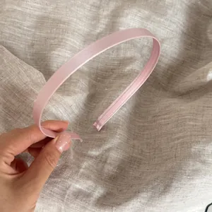 Vista detallada de una diadema fina de satén rosa claro para peinados de mujer