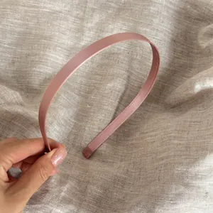 Detalle de una diadema fina de satén rosa sobre un fondo de tela de lino natural