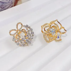 Detailansicht von eleganten goldenen Kamelien- und Schleifen-Schalringen mit Strass