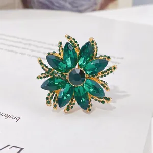 Detailansicht einer vintage grünen Kristall-Blumen-Schalschnalle mit Goldoberfläche.