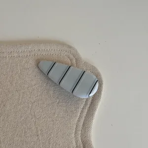 Détail macro d'une pince à cheveux minimaliste à rayures bleu clair sur tissu beige