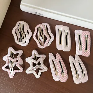 Macro view showing pink plaid and polka dot fabric hair clips in star and wave shapes