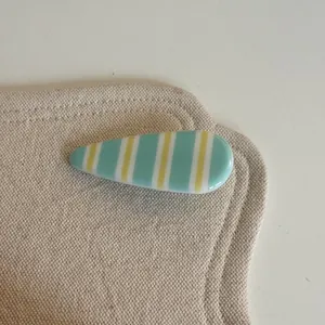 Vue détaillée d'une pince à cheveux coréenne élégante à rayures vert menthe et jaunes