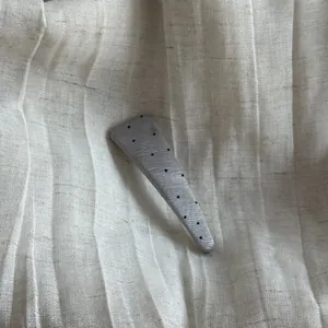 Close-up detail of a silver textured triangle hair clip with stylish black polka dots