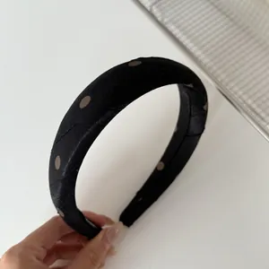 Detail des schwarzen gepolsterten Haarreifs mit Retro-Punkten und Faltenstruktur.