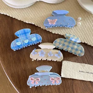 Detailed view of five blue and beige acetate hair claw clips with bow and floral accents