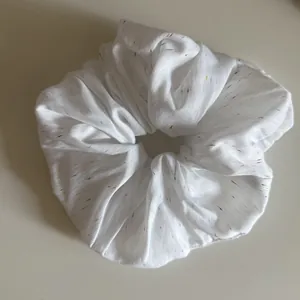 Großaufnahme eines weißen Scrunchies mit bunten Konfetti-Sprenkeln Stoffdetail
