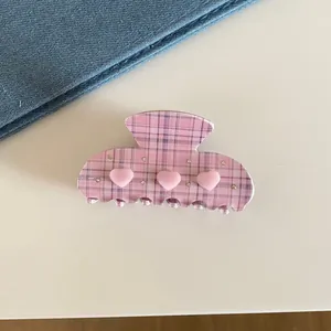 Close-up of a French style pink plaid hair claw clip with hearts and rhinestones