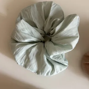 Detailansicht eines großen mintgrünen Scrunchies mit bunter Konfetti-Textur für Haare.