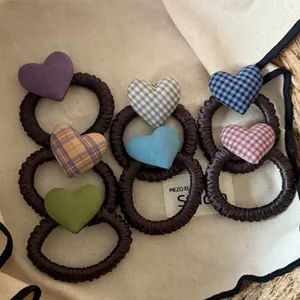 Detalle de varios coleteros para el pelo en forma de corazón con motivos de cuadros.