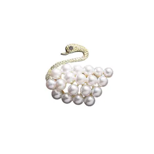 Elegant swan brooch with white pearls and golden textured metal on white background.
