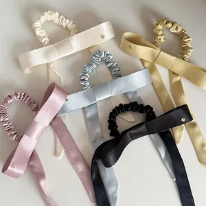 Gedetailleerde close-up van elegante satijnen haarelastiekjes met strik in pastelkleuren.