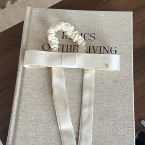 Detailopname van een crèmekleurige satijnen haarelastiek met strik op een vintage boek