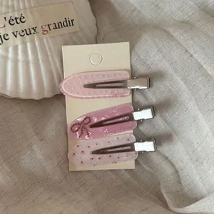 Close-up of three sweet pink hair clips with polka dots, bows, and dainty floral patterns.