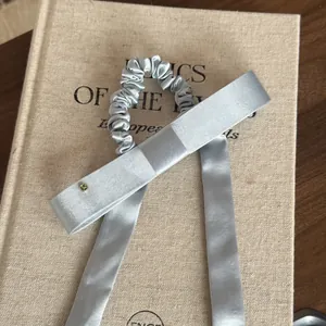 Detailopname van een elegante zilveren satijnen scrunchie met lange linten op een boek