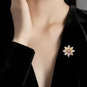 Elegante broche flor de nieve con piedras ojo de gato sobre blazer de terciopelo negro