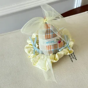 Detailed view of a cute Korean style party hat hair clip with yellow mesh bow and plaid fabric