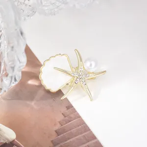 Detailansicht einer eleganten Seestern und Muschel Perlenbrosche mit funkelnden Kristallen