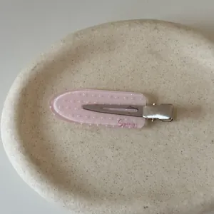 Detailed macro view of a pink polka dot hair clip with Spring engraving on a tray