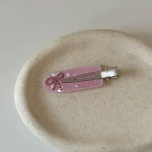 Close-up detail of a pink marbled acetate hair clip with an elegant rhinestone bow