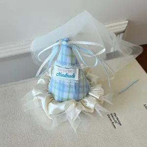 Detail of blue plaid party hat hair clip with ribbon bow and soft white tulle veil.
