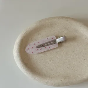 Detailed view of a pink floral acetate hair clip on a minimalist ceramic tray