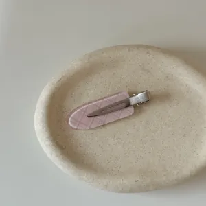 Macro view of a pink plaid pattern seamless hair clip resting on a textured tray