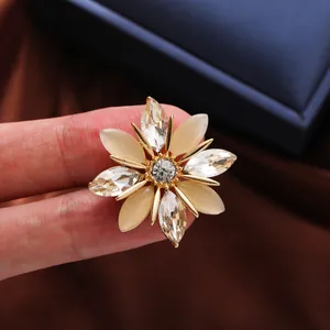 Detalle de un elegante broche de copo de nieve con piedras de ojo de gato y cristales.