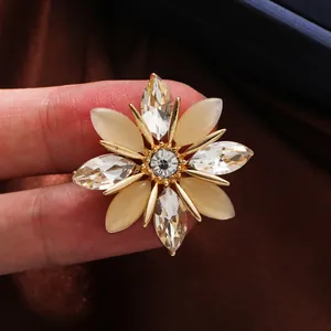 Primer plano de un broche de copo de nieve dorado con cristal tallado y piedras de ojo de gato