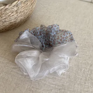 Close-up detail of a two-tone leopard print mesh scrunchie on a textured linen background