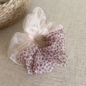 Close-up detail of a dual-texture mesh scrunchie with leopard print and cream organza.