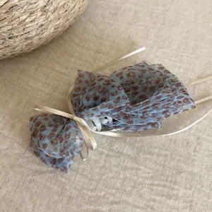 Detail view of leopard print mesh hair claw clip with ribbon bow on linen background
