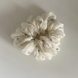 Close-up of off-white scrunchie with blue floral pattern and textured fabric