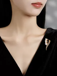 Close-up detail of luxury gold-toned lily of the valley brooch on black velvet garment