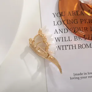 Detailed back view of a gold-tone Lily of the Valley brooch on a clean white surface