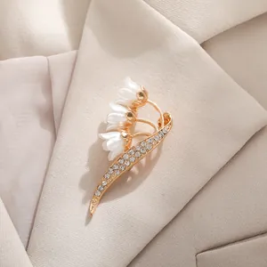 Elegant lily of the valley brooch with white petals and rhinestones on a beige blazer