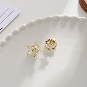 Nahaufnahme einer goldenen Blumenbrosche mit Kristallen und Verschlussdetails