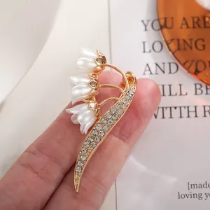 Close-up detail showing the intricate crystal inlay and pearl buds of the lily brooch