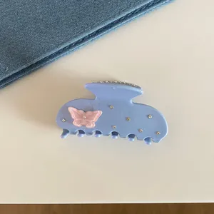 Close-up of blue hair claw clip featuring pink butterfly and rhinestone details
