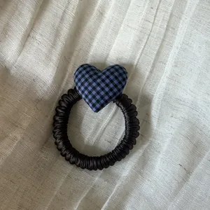 Primer plano detallado de un coletero con corazón de cuadros azules sobre tela texturizada