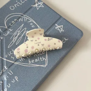 Close-up of a French vintage acetate hair claw clip with rhinestones and floral patterns.